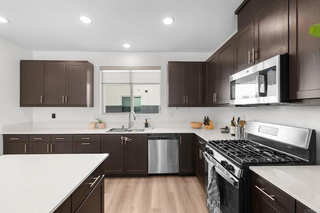 5485 Seacliff Pl Unit 106, San Diego, CA 92154 - kitchen with stainless steel appliances, a sink, light countertops, dark brown cabinetry, and light wood finished floors