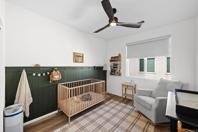 5485 Seacliff Pl Unit 106, San Diego, CA 92154 - bedroom featuring wood finished floors, a crib, a ceiling fan, and a wainscoted wall