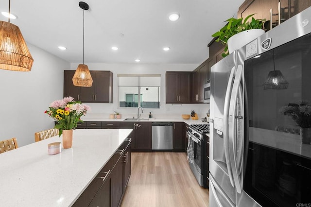 5485 Seacliff Pl Unit 106, San Diego, CA 92154 - kitchen with appliances with stainless steel finishes, a sink, dark brown cabinetry, light wood-style floors, and pendant lighting