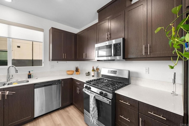 5485 Seacliff Pl Unit 106, San Diego, CA 92154 - kitchen featuring appliances with stainless steel finishes, a sink, dark brown cabinetry, light wood-style floors, and light countertops