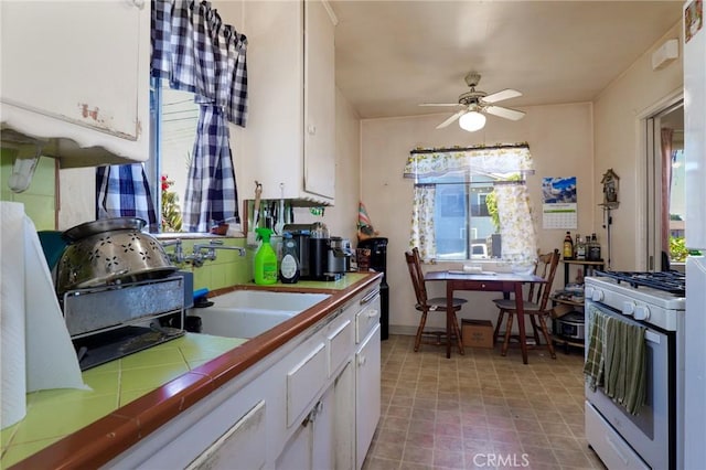 1716 N Fries Ave, Wilmington, CA 90744 - kitchen with white gas range oven, tile counters, white cabinetry, and healthy amount of natural light