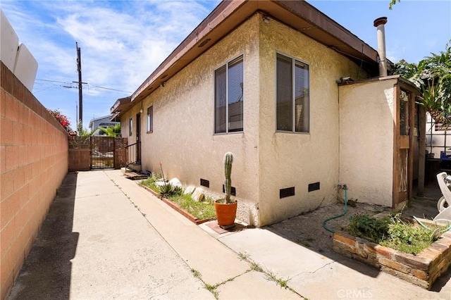 1716 N Fries Ave, Wilmington, CA 90744 - view of side of home featuring a gate, crawl space, and stucco siding