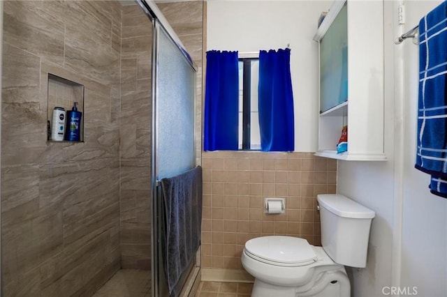 1716 N Fries Ave, Wilmington, CA 90744 - full bath featuring tile walls, a shower stall, toilet, tile patterned flooring, and a wainscoted wall