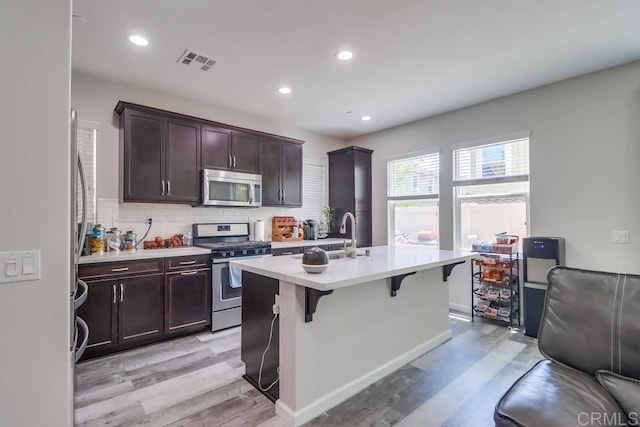13217 Midnight Star Way, Lakeside, CA 92040 - kitchen with appliances with stainless steel finishes, light countertops, light wood-style floors, backsplash, and a breakfast bar area