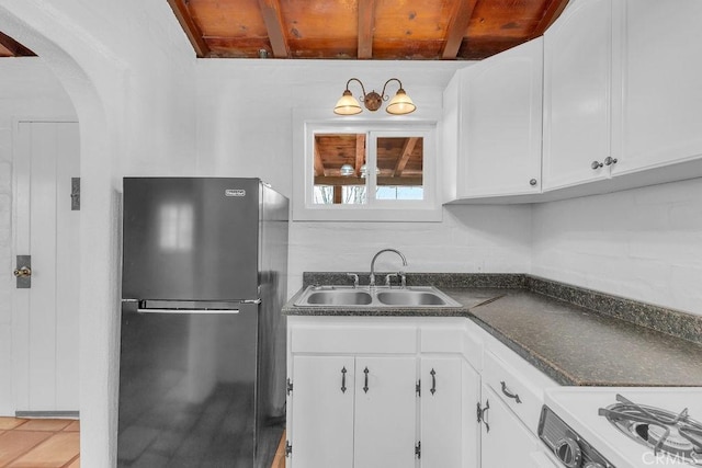 6365 Cahuilla Ave Unit 29, Palms, CA 92277 - kitchen with freestanding refrigerator, a sink, dark countertops, white cabinets, and arched walkways