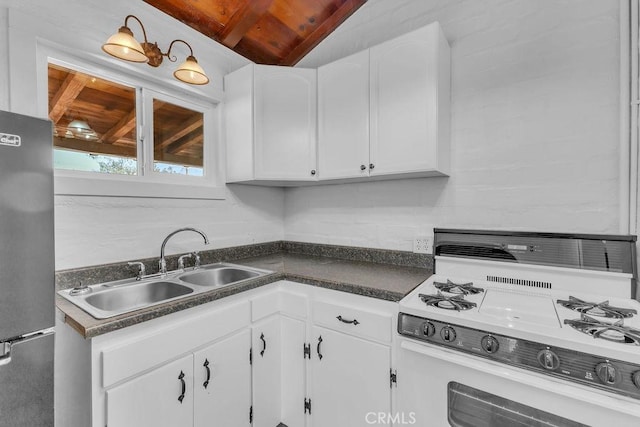 6365 Cahuilla Ave Unit 29, Palms, CA 92277 - kitchen featuring white gas range oven, freestanding refrigerator, dark countertops, white cabinets, and a sink