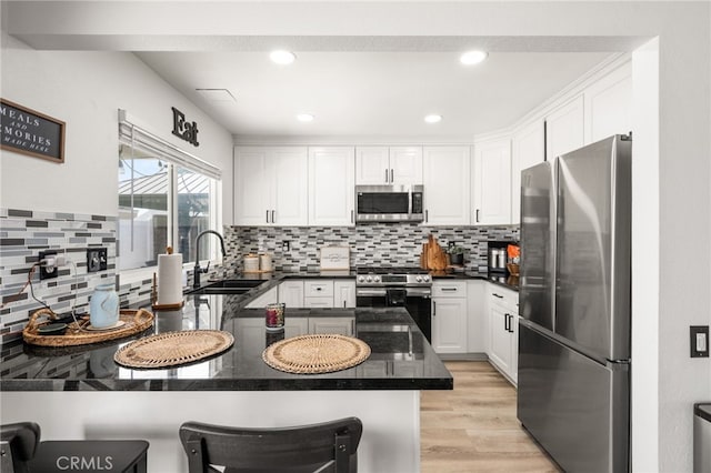 1138 Millstream Ln, Corona, CA 92878 - kitchen with stainless steel appliances, a sink, a peninsula, white cabinets, and light wood-style floors