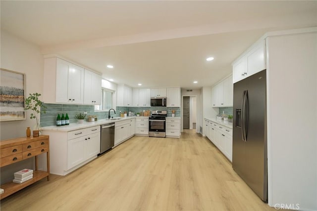 25810 San Felipe Dr, Hemet, CA 92544 - kitchen with appliances with stainless steel finishes, a sink, light wood-style floors, white cabinets, and decorative backsplash