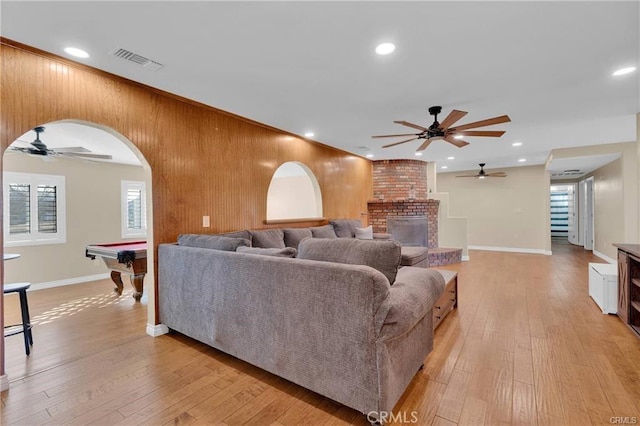 19055 Seaforth St, Hesperia, CA 92345 - living room with a ceiling fan, a brick fireplace, arched walkways, plenty of natural light, and wood walls