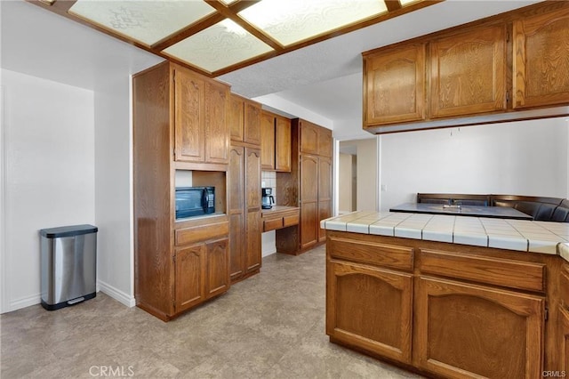 19055 Seaforth St, Hesperia, CA 92345 - kitchen with brown cabinets, tile countertops, and black microwave