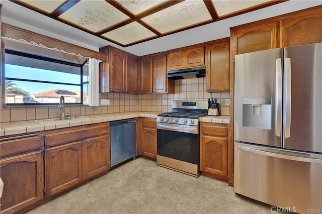 19055 Seaforth St, Hesperia, CA 92345 - kitchen with stainless steel appliances, tile counters, a sink, under cabinet range hood, and decorative backsplash
