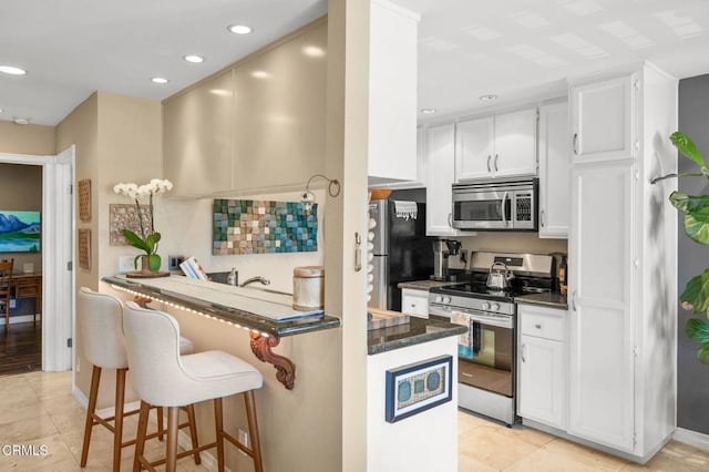 2623 Antonio Dr Unit 104, Camarillo, CA 93010 - kitchen with stainless steel appliances, a kitchen bar, white cabinets, recessed lighting, and a peninsula