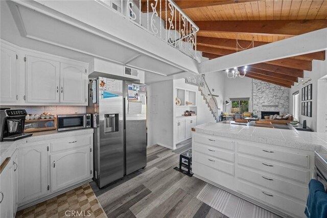 40901 Gibbel Rd, Hemet, CA 92544 - kitchen with stainless steel appliances, white cabinets, wooden ceiling, light wood-type flooring, and a stone fireplace