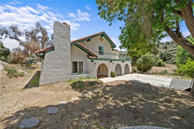 40901 Gibbel Rd, Hemet, CA 92544 - rear view of property featuring concrete driveway, a balcony, a chimney, stucco siding, and a tiled roof