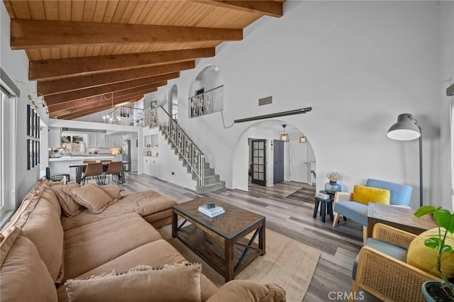 40901 Gibbel Rd, Hemet, CA 92544 - living room featuring arched walkways, wooden ceiling with exposed beams, stairway, light wood-style floors, and high vaulted ceiling