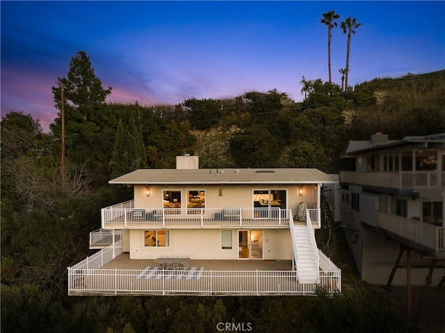 3721 Glenridge Dr, Sherman Oaks, CA 91423 - back of property at dusk featuring stairs, stucco siding, a chimney, and a view of trees