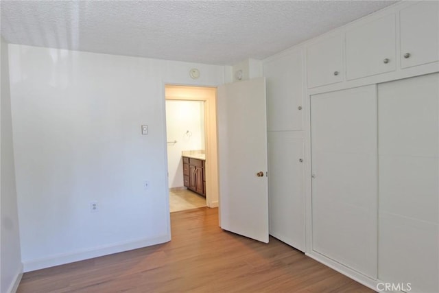 368 Avenida Castilla Unit C, Laguna Woods, CA 92637 - unfurnished bedroom with light wood-style floors, a textured ceiling, a closet, and baseboards