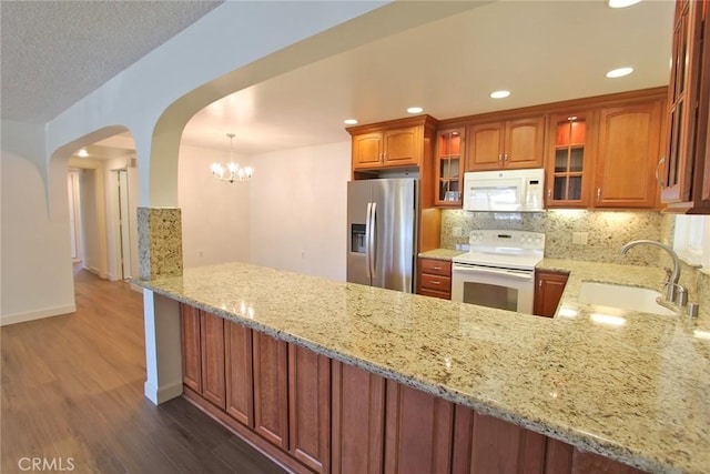 368 Avenida Castilla Unit C, Laguna Woods, CA 92637 - kitchen with white appliances, a sink, wood finished floors, glass insert cabinets, and light stone counters