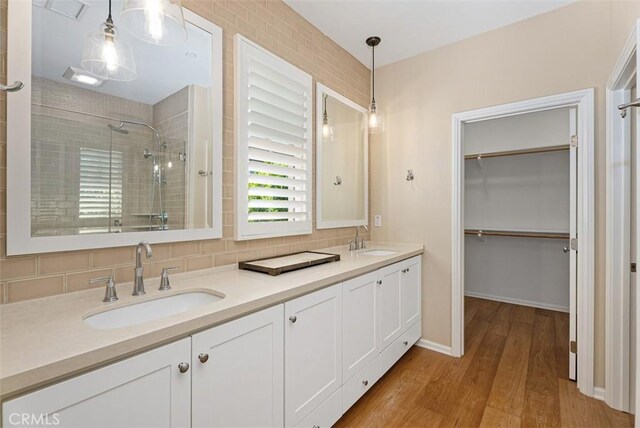 104 Working, Irvine, CA 92602 - bathroom featuring a tile shower, wood finished floors, double vanity, a spacious closet, and baseboards