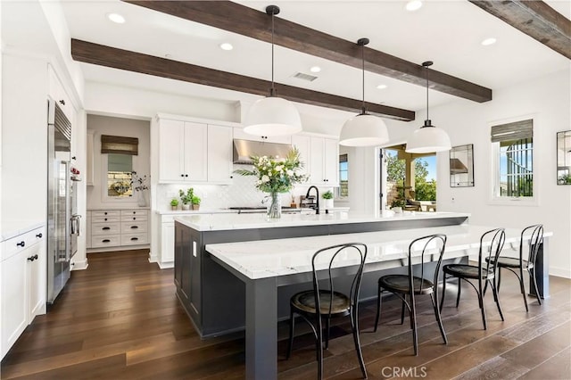 101 Via Almodovar, San Clemente, CA 92672 - kitchen with a large island with sink, dark wood-style floors, a breakfast bar, white cabinets, and decorative backsplash