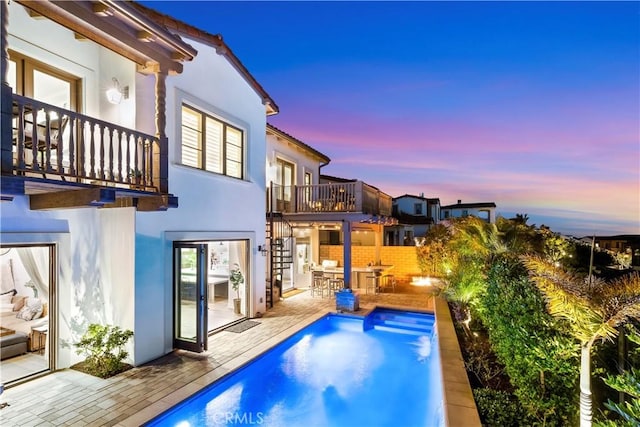 101 Via Almodovar, San Clemente, CA 92672 - back of property at dusk featuring a balcony, stucco siding, stairway, and an outdoor pool