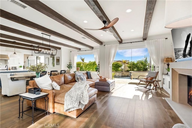 101 Via Almodovar, San Clemente, CA 92672 - living room with beamed ceiling, a warm lit fireplace, dark wood finished floors, and a ceiling fan