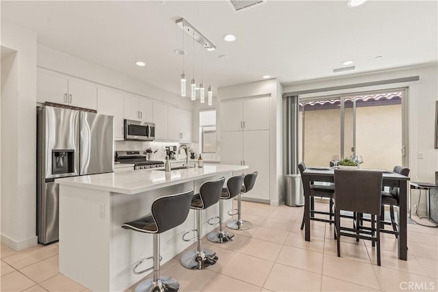 80281 Redstone Way, La Quinta, CA 92253 - kitchen featuring appliances with stainless steel finishes, a sink, light countertops, a kitchen breakfast bar, and white cabinetry