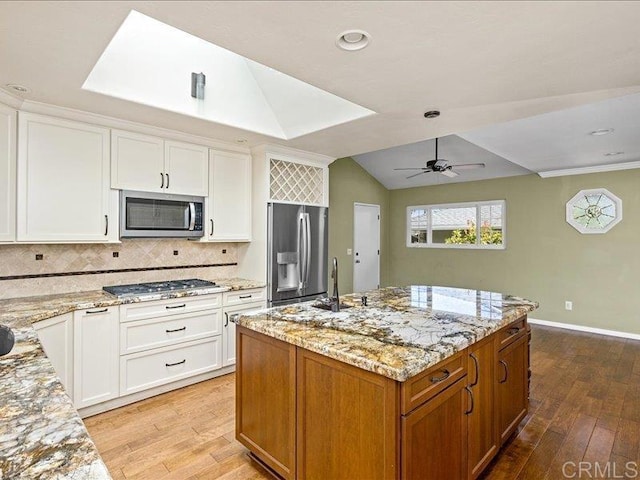1051 La Reina, San Marcos, CA 92078 - kitchen with stainless steel appliances, light wood-type flooring, a ceiling fan, tasteful backsplash, and light stone counters