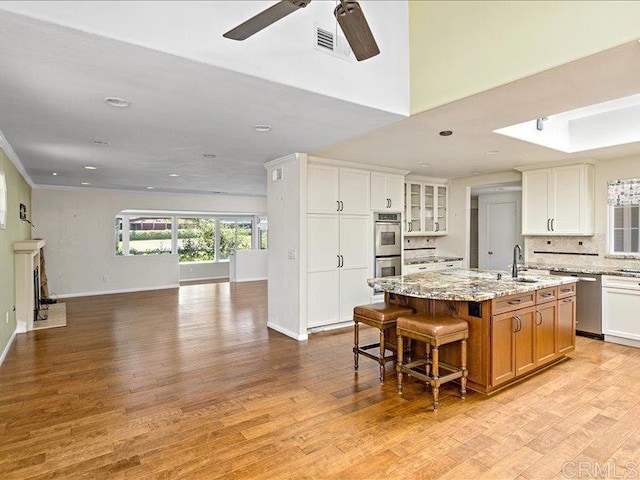 1051 La Reina, San Marcos, CA 92078 - kitchen with open floor plan, an island with sink, a ceiling fan, light wood finished floors, and tasteful backsplash