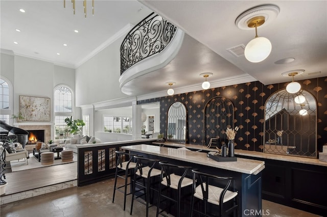 5 Hillsborough, Newport Beach, CA 92660 - kitchen featuring light countertops, a breakfast bar area, a towering ceiling, a warm lit fireplace, and concrete flooring