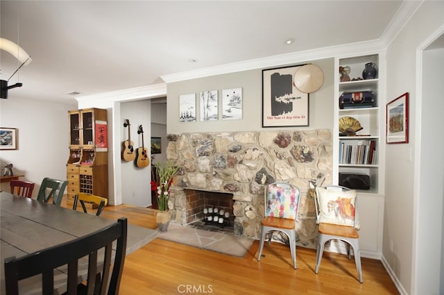 7235 Estepa Dr, Tujunga, CA 91042 - dining area featuring wood finished floors, crown molding, a fireplace, and built in shelves
