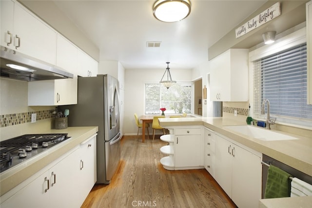 7235 Estepa Dr, Tujunga, CA 91042 - kitchen with under cabinet range hood, stainless steel appliances, light wood finished floors, white cabinets, and a peninsula