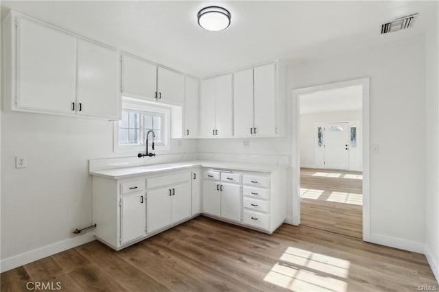 390 E 4th St, San Bernardino, CA 92410 - kitchen with a sink, light countertops, baseboards, light wood-type flooring, and white cabinets