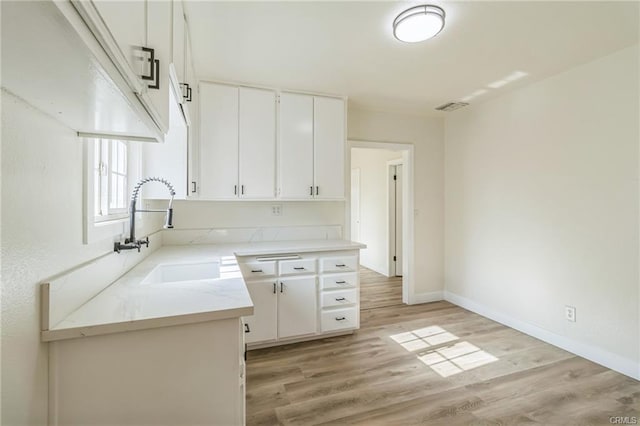 390 E 4th St, San Bernardino, CA 92410 - kitchen featuring a sink, light wood-style flooring, white cabinets, and baseboards