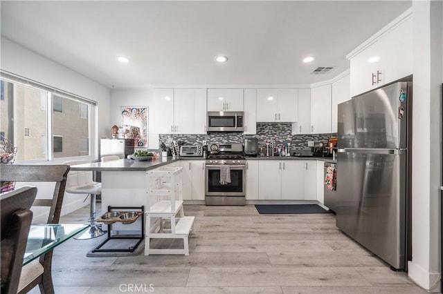 9950 Topanga Canyon Blvd Unit 5, Chatsworth, CA 91311 - kitchen featuring appliances with stainless steel finishes, dark countertops, a peninsula, light wood-type flooring, and recessed lighting
