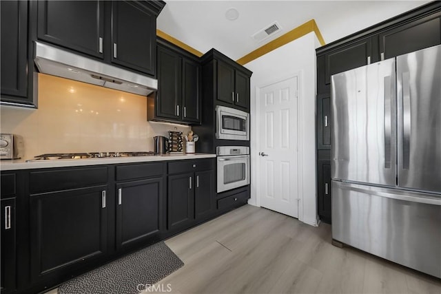 43228 Bacino Ct, Indio, CA 92203 - kitchen featuring appliances with stainless steel finishes, under cabinet range hood, dark cabinets, and light countertops