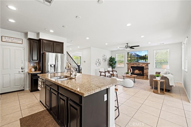 29015 Ridgecrest Ct, Valencia, CA 91354 - kitchen featuring appliances with stainless steel finishes, a sink, light tile patterned floors, a stone fireplace, and an island with sink