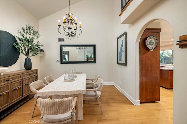 16561 Wanderer Ln, Huntington Beach, CA 92649 - dining space featuring arched walkways, a chandelier, light wood-type flooring, baseboards, and high vaulted ceiling