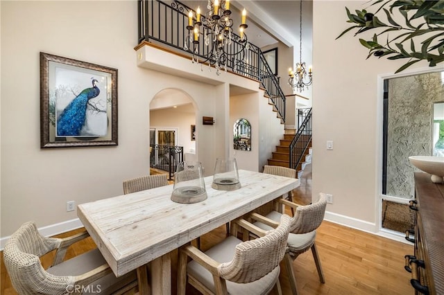 16561 Wanderer Ln, Huntington Beach, CA 92649 - dining room featuring a chandelier, arched walkways, light wood-style floors, stairway, and baseboards