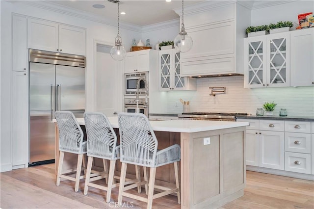2001 Oak Ave, Manhattan Beach, CA 90266 - kitchen featuring built in appliances, light wood finished floors, an island with sink, backsplash, and crown molding