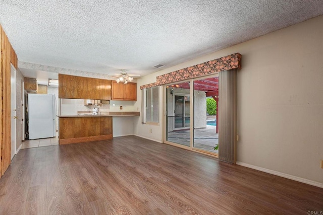 9336 Nalini Ct, Santee, CA 92071 - kitchen with freestanding refrigerator, wood finished floors, brown cabinetry, a textured ceiling, and light countertops