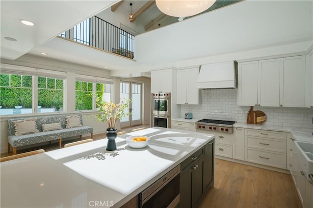 2104 Flournoy Rd, Manhattan Beach, CA 90266 - kitchen featuring custom range hood, stainless steel appliances, light wood-style flooring, light countertops, and decorative backsplash
