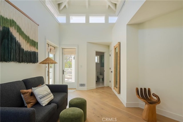 2104 Flournoy Rd, Manhattan Beach, CA 90266 - living room featuring light wood-style floors, baseboards, beam ceiling, and a towering ceiling