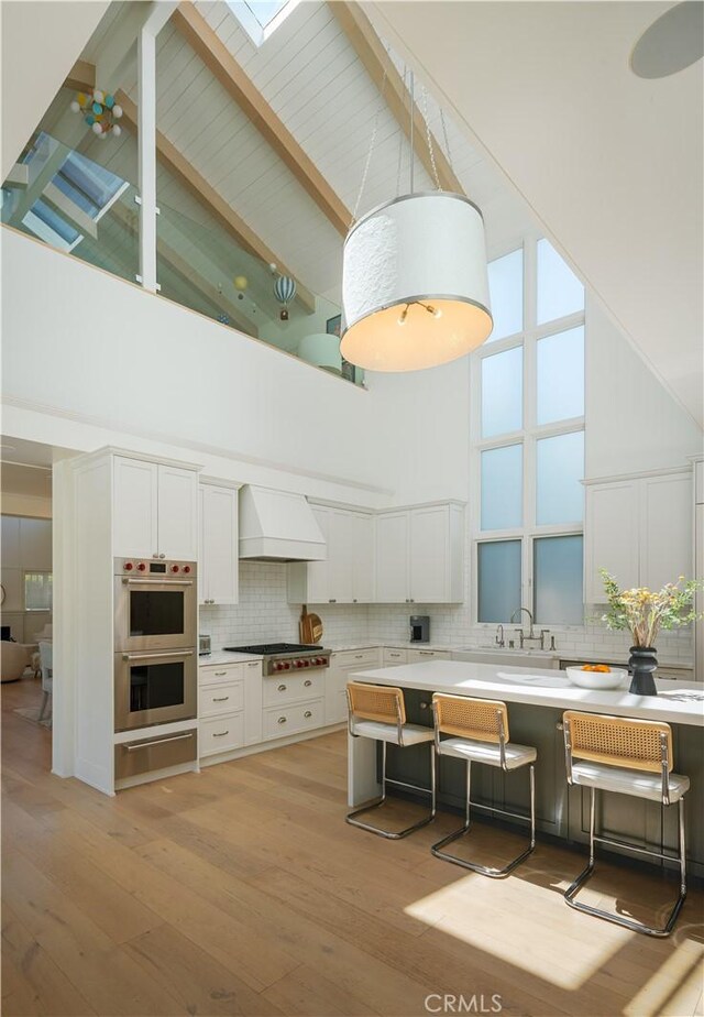 2104 Flournoy Rd, Manhattan Beach, CA 90266 - kitchen with high vaulted ceiling, custom exhaust hood, appliances with stainless steel finishes, white cabinets, and tasteful backsplash