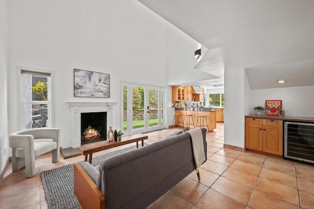 1033 Via Mil Cumbres, Solana Beach, CA 92075 - living area with beverage cooler, a warm lit fireplace, healthy amount of natural light, light tile patterned floors, and a high ceiling
