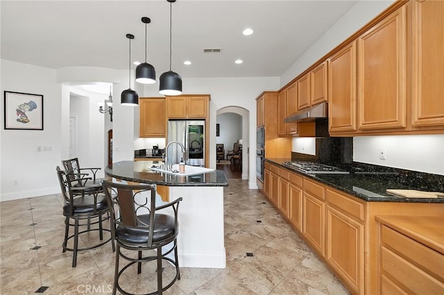 44774 Pride Mountain St, Temecula, CA 92592 - kitchen with arched walkways, stainless steel appliances, a sink, under cabinet range hood, and a breakfast bar