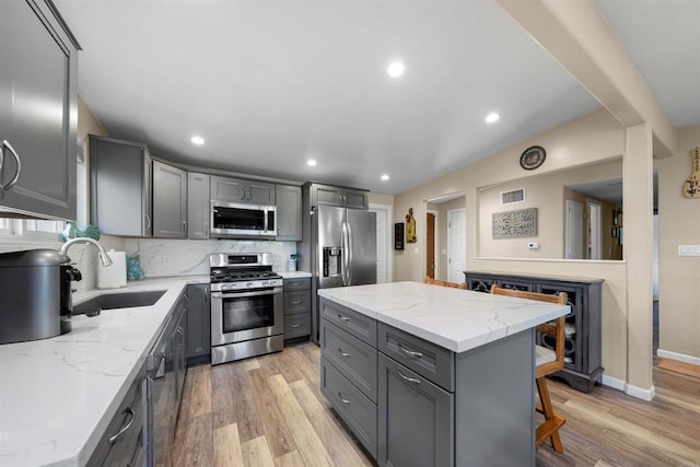 5680 Wendi St, La Mesa, CA 91942 - kitchen featuring appliances with stainless steel finishes, gray cabinets, a sink, light wood finished floors, and decorative backsplash