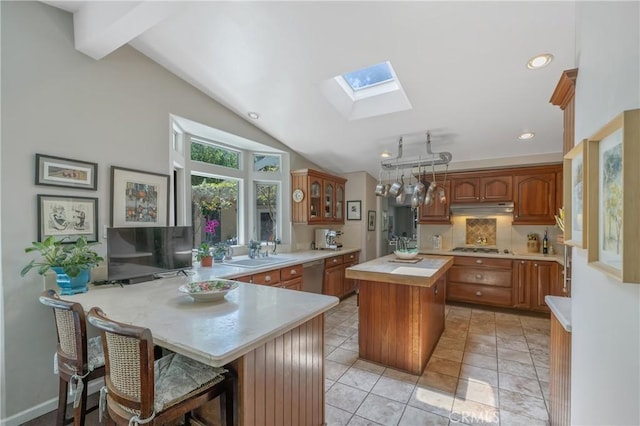 3818 Hayvenhurst Ave, Encino, CA 91436 - kitchen featuring a skylight, under cabinet range hood, stainless steel dishwasher, a peninsula, and a kitchen island