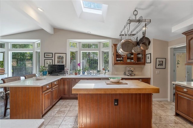 3818 Hayvenhurst Ave, Encino, CA 91436 - kitchen featuring a peninsula, a breakfast bar, a skylight, light tile patterned floors, and vaulted ceiling
