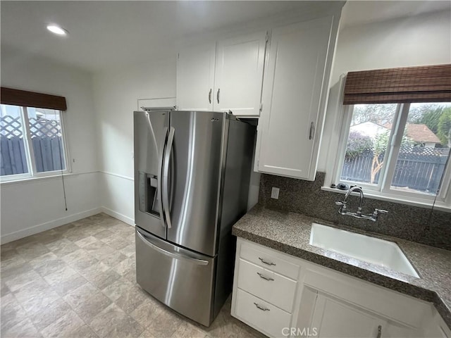 2221 Granada Ave, Long Beach, CA 90815 - kitchen featuring stainless steel fridge with ice dispenser, a sink, white cabinets, baseboards, and backsplash